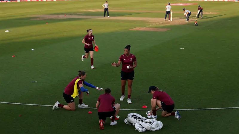 Medium shot of a women's cricket fielding circle adjusting before a delivery with the bowler at the top of her mark